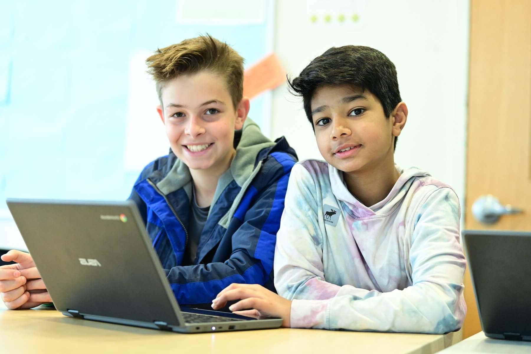 道德文化菲尔德斯顿中学的学生们一起在电脑上工作，停下来对着镜头微笑