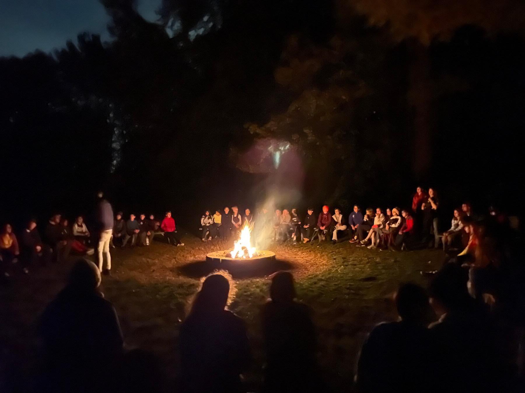 道德文化的学生，教师和工作人员聚集在篝火在晚上.