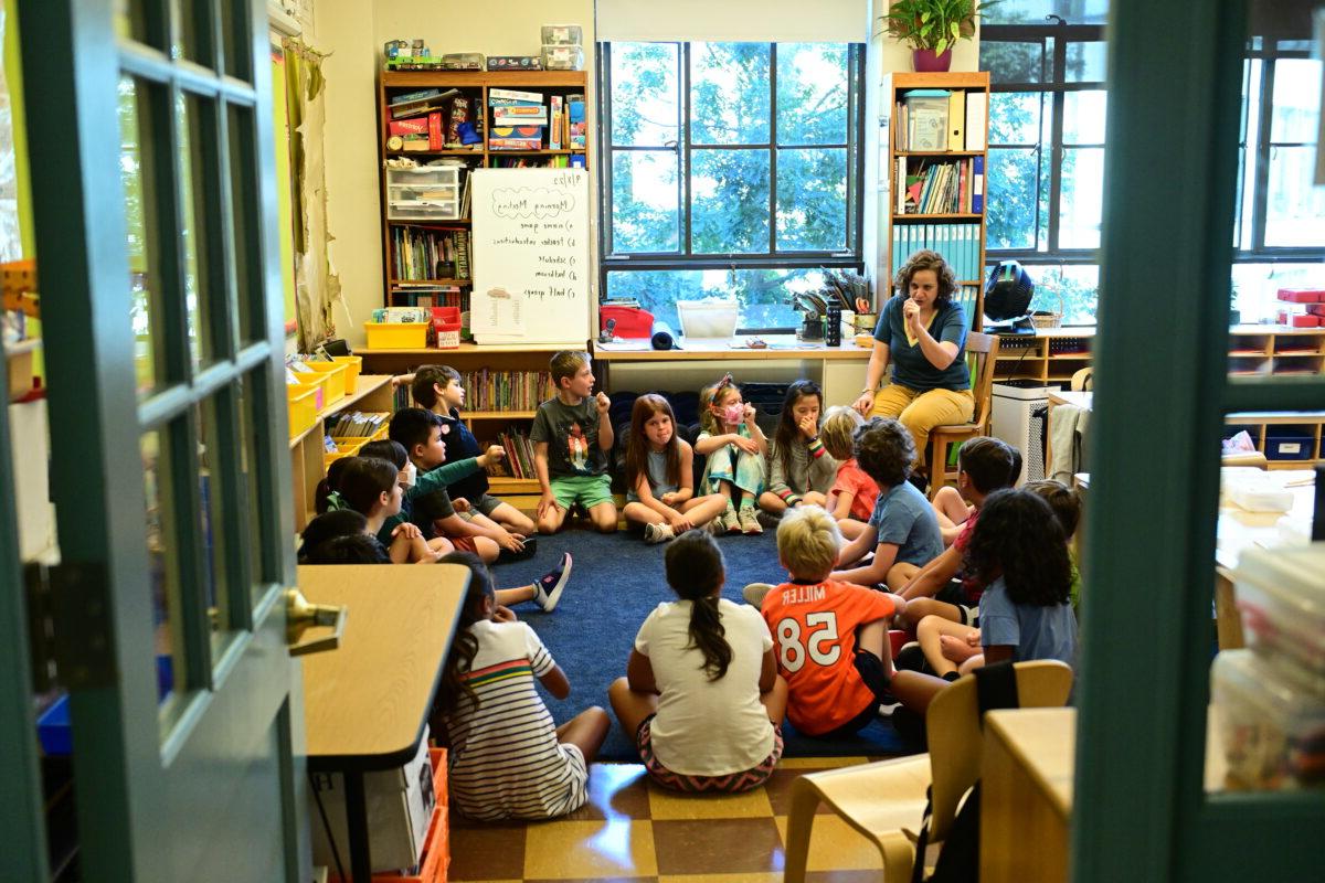 在菲尔德斯顿小学，一群学生围成一圈看着他们的老师