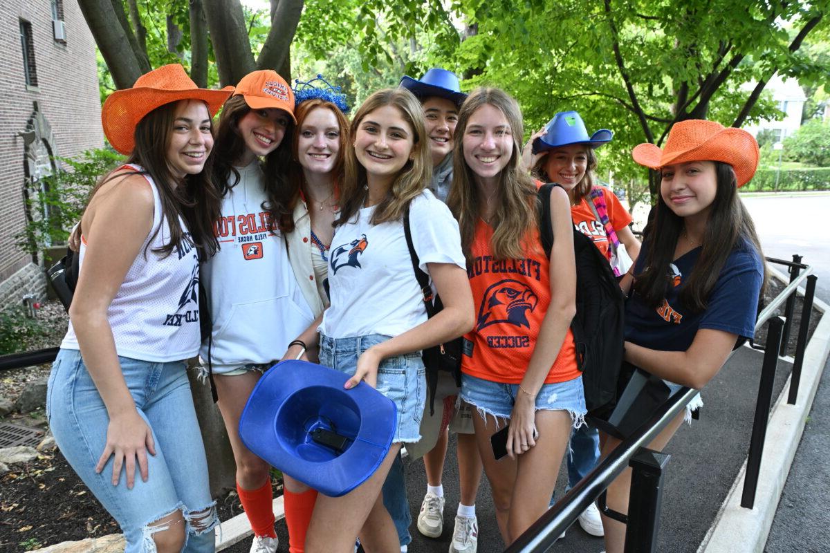 一群菲尔德斯顿高中的学生穿着ECFS的装备，戴着橙色和蓝色的帽子，在镜头前摆姿势