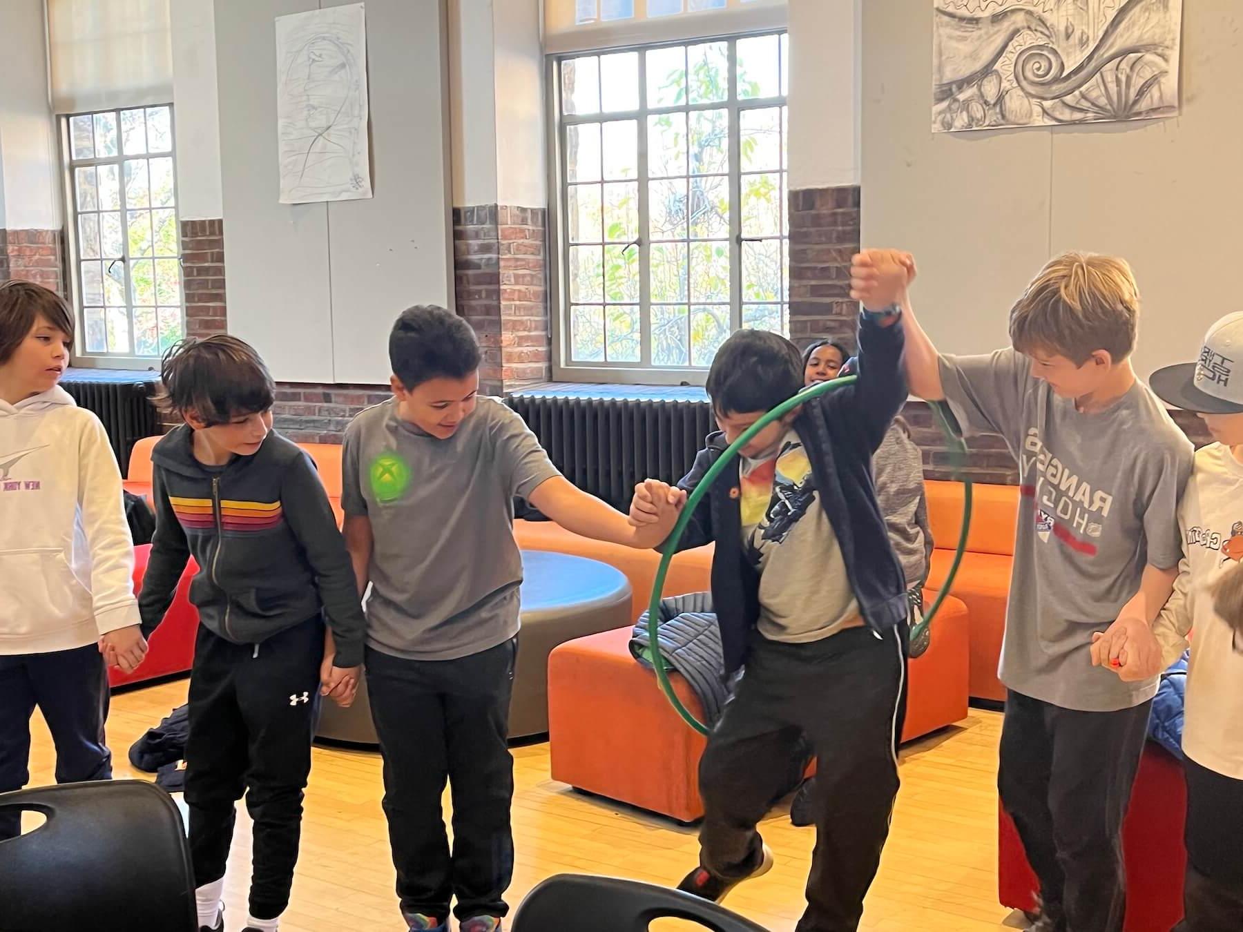 Ethical Culture Fieldston School Fieldston Lower students participating in team building activity by passing a hola hoop around a circle