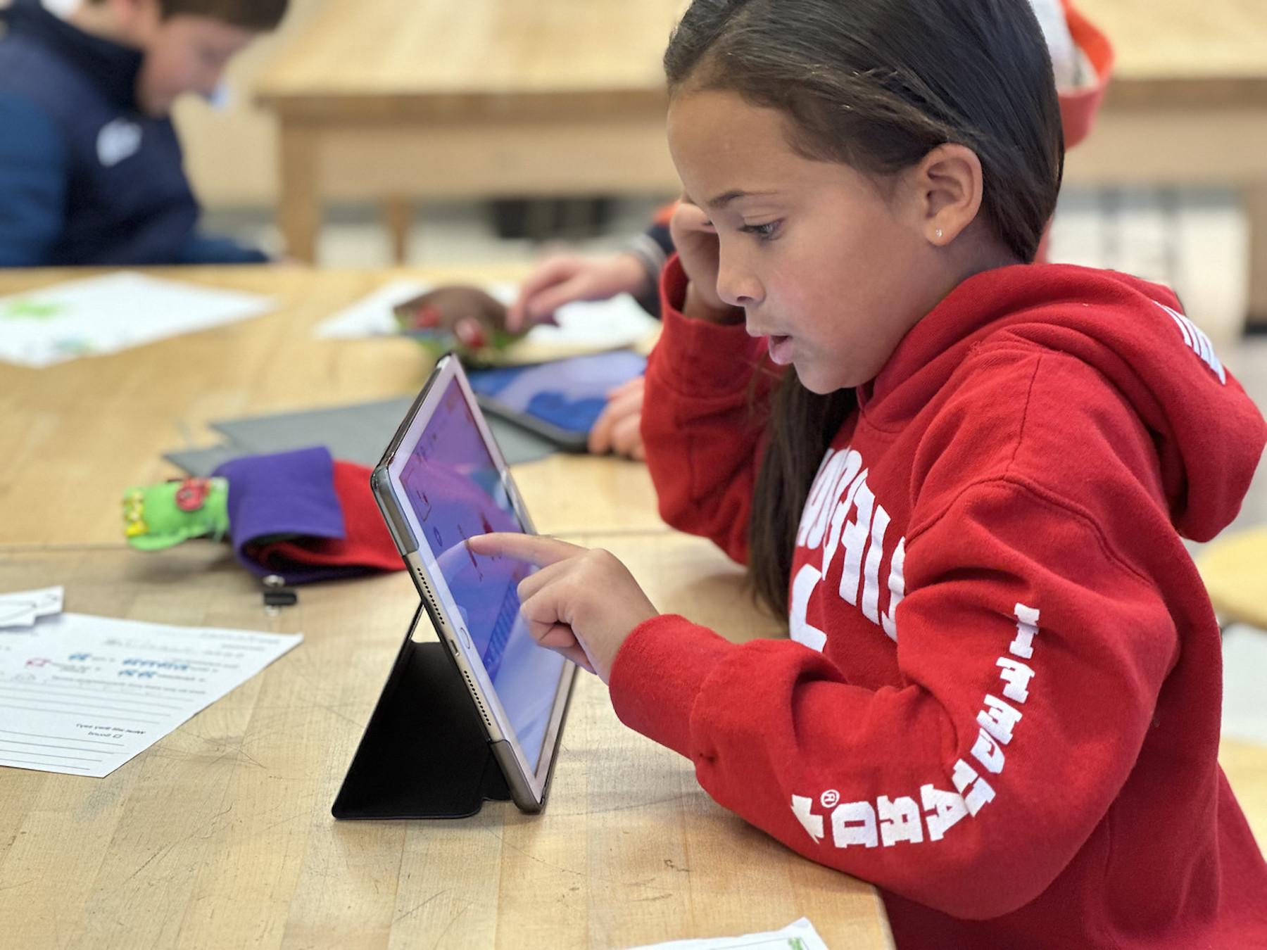 菲尔德斯顿低年级学生坐在桌子前用iPad工作.