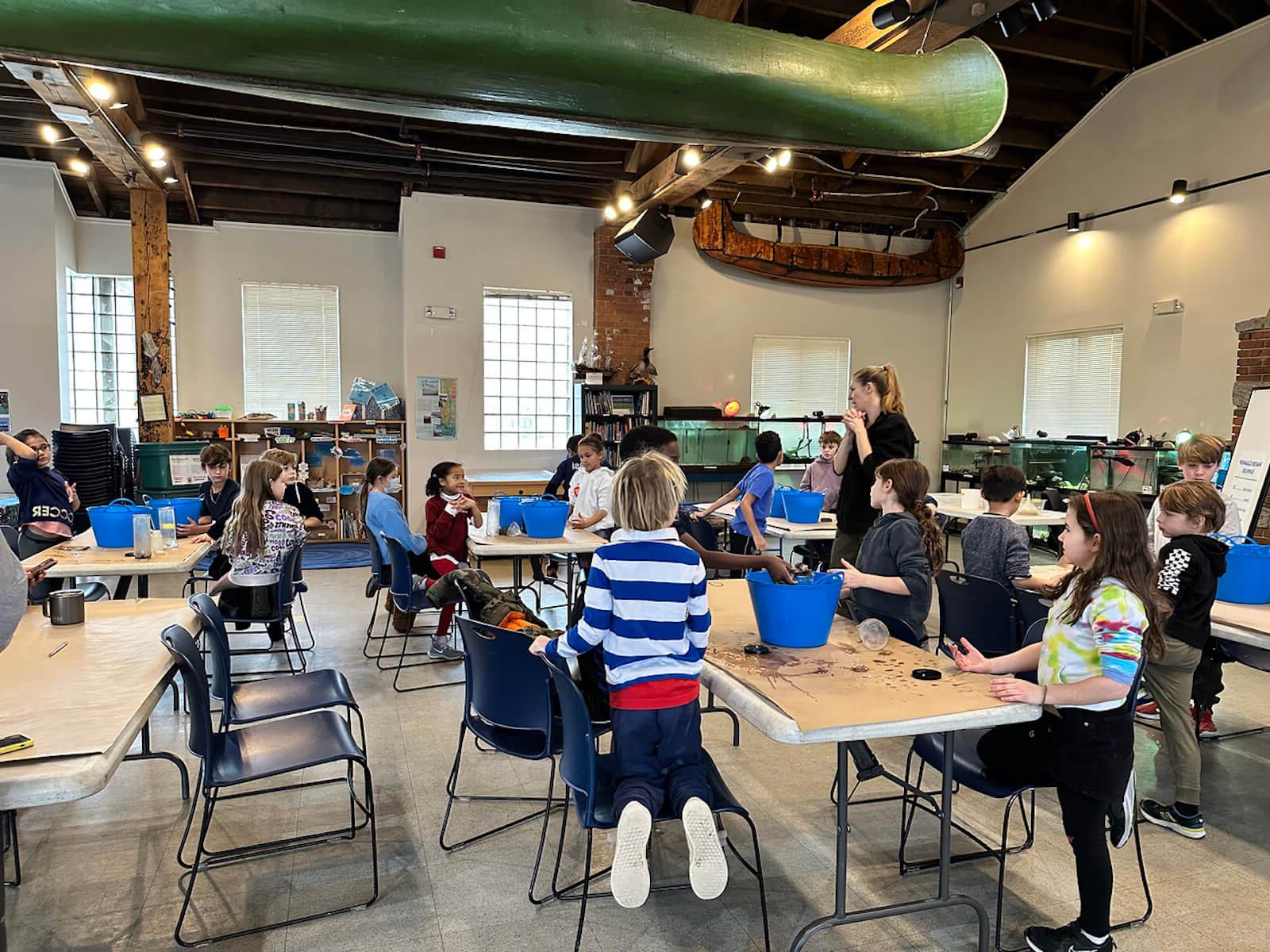 Fieldston Lower students listen to "Water Inspector" and filter dirty water using supplies such as a filter and cotton balls at the Beczak Center.