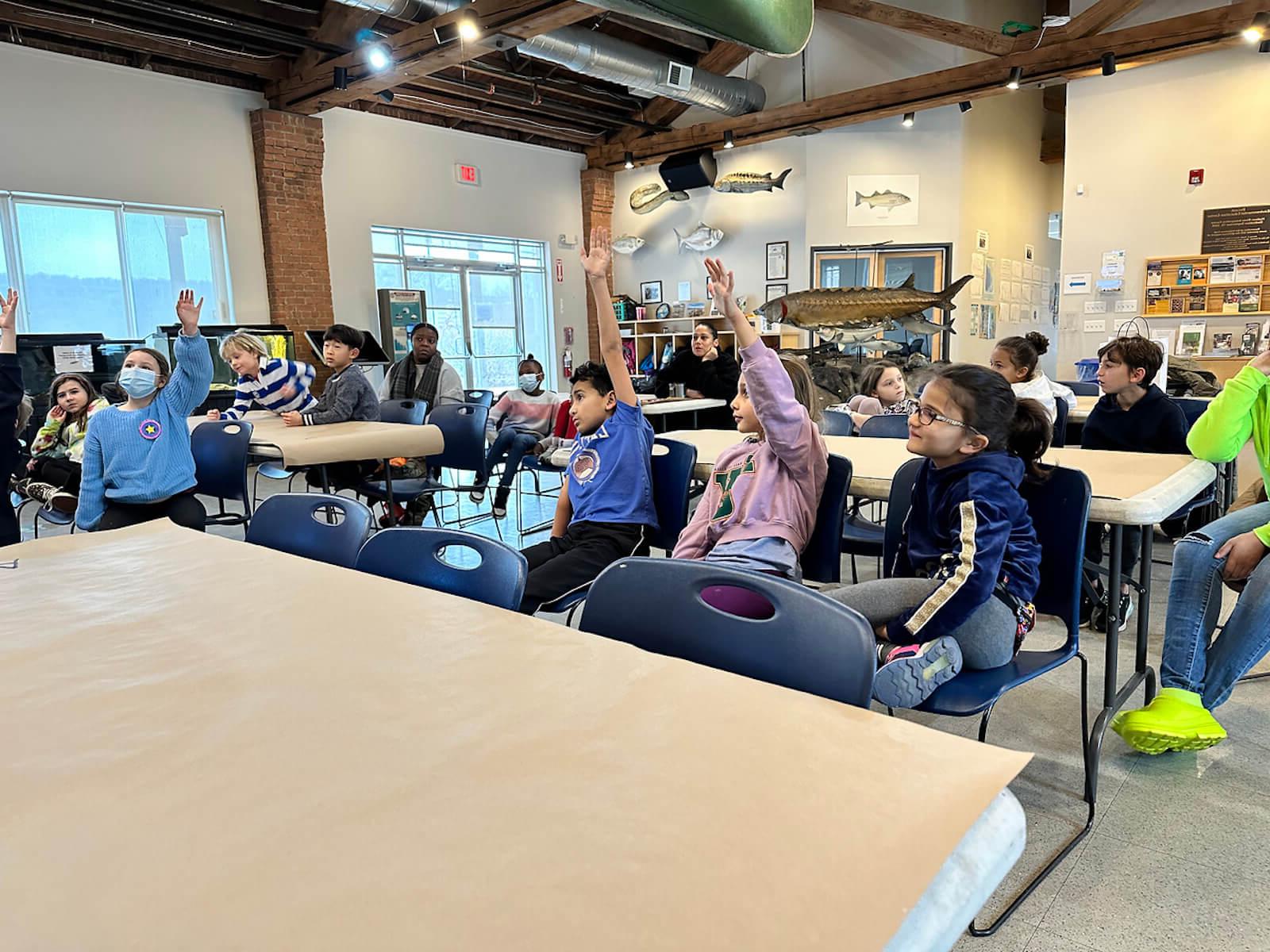 Fieldston Lower students raise their hands to contribute to a conversation about water pollution at the Beczak Center.
