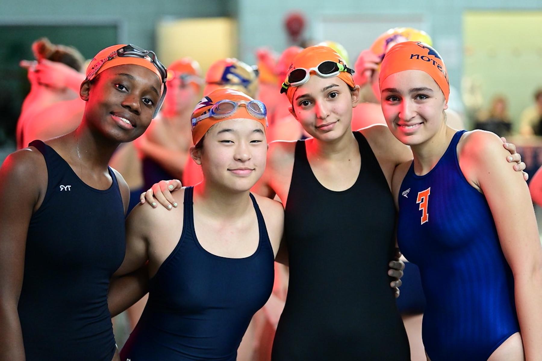 四名菲尔德斯顿上游游泳运动员对着镜头摆姿势微笑.