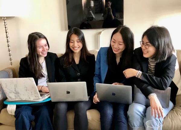 女性金融俱乐部的四名成员坐在电脑前微笑