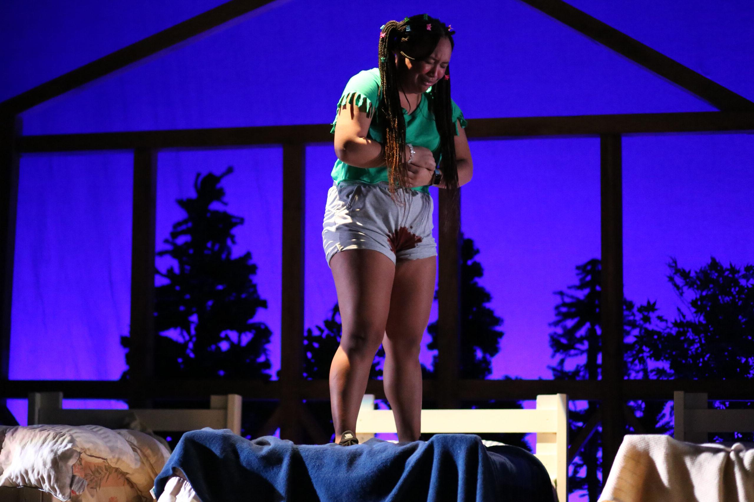 Upper School student crying and holding her stomach on stage during the fall theatre production
