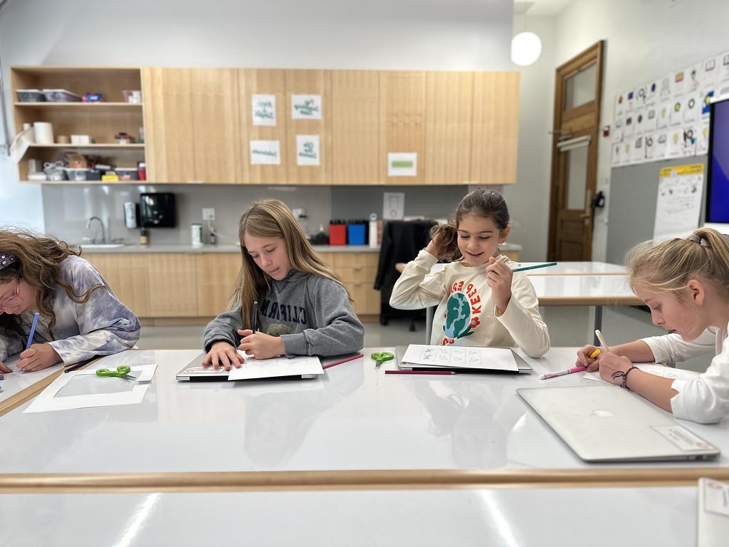 道德 Culture students sit at desks and work on animation project together.